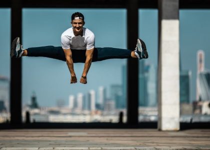 Man performing a split jump on concrete, showcasing fitness and agility.